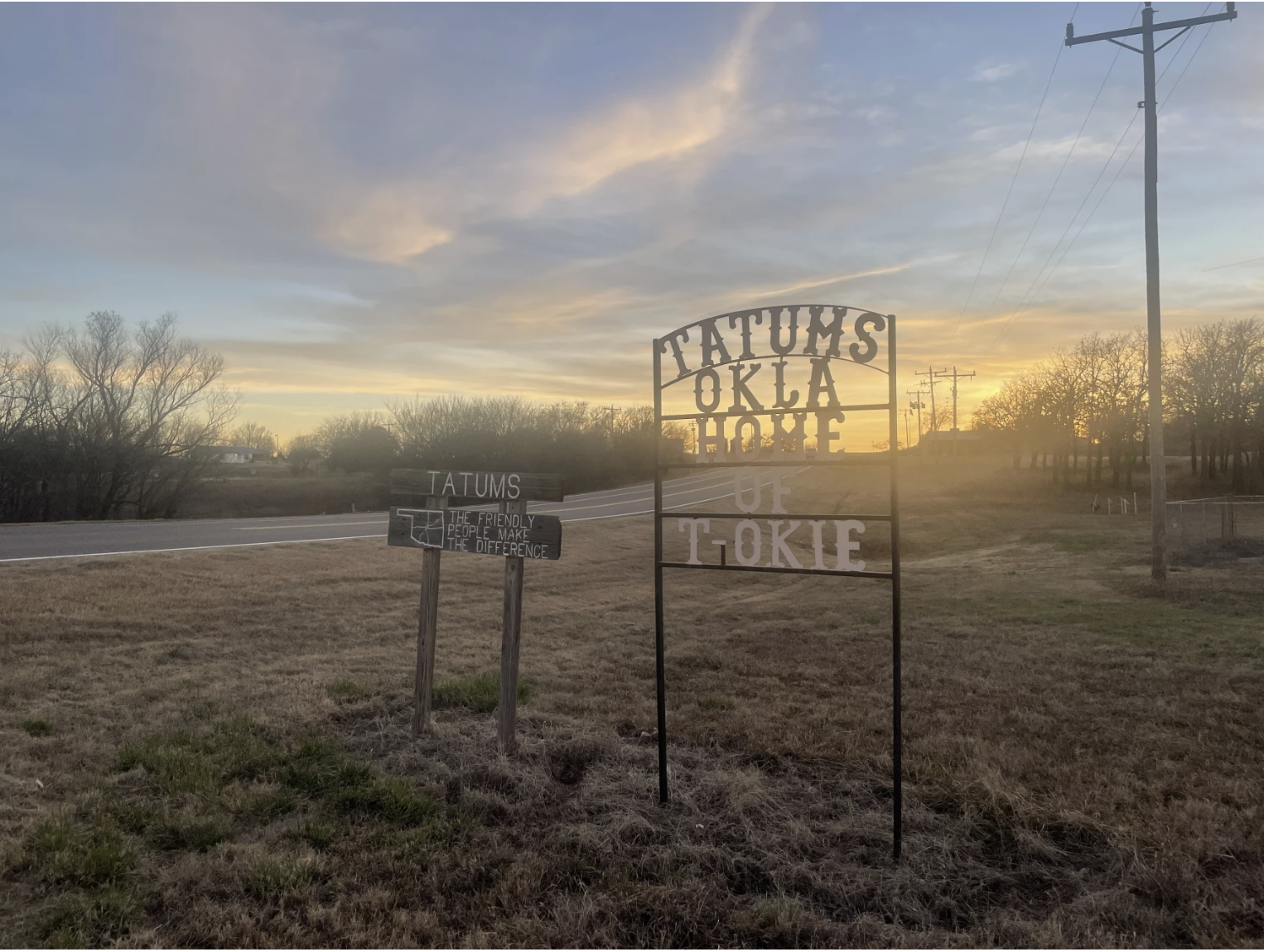 Two road signs in Tatums, Oklahoma. One reads "TATUMS: The friendly people make the difference," and the other "Tatums, Okla: Home of T-Okie."